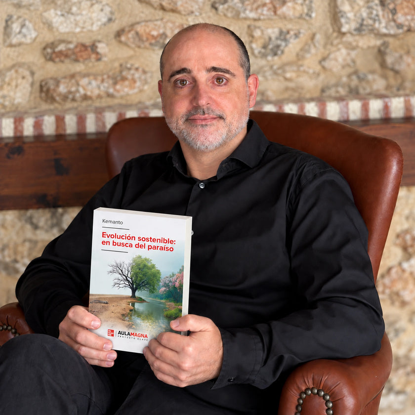 KEMANTO mira a cámara sentado en un sillón, sosteniendo su libro «Evolución sostenible: en busca del paraíso»